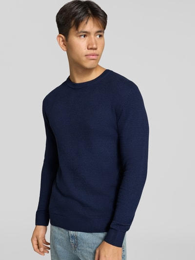 Männermodel trägt Strickpullover aus reiner Baumwolle Modell 'Ryder' von JACK & JONES in Dunkelblau mit Rundhalsausschnitt, Ganzkörperansicht von vorne