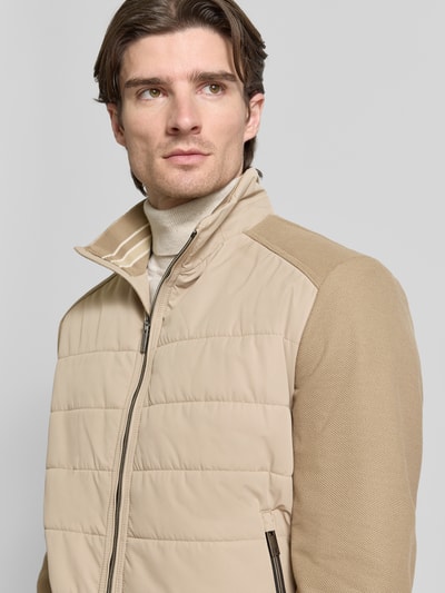 Männermodel trägt Jacke mit Stehkragen von Christian Berg Men in Beige mit Reißverschluss und gerippten Abschlüssen, Nahaufnahme Oberkörper. Regular Fit, Reißverschlusstaschen, Maße laut Größe M.
