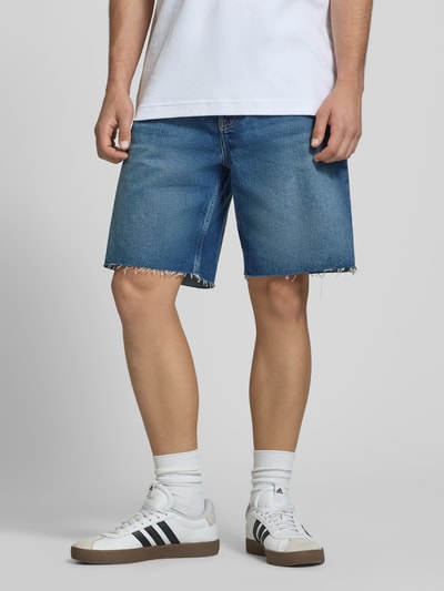 Männermodel trägt Relaxed Fit Bermudas aus reiner Baumwolle Modell 'GREENWOOD' von Calvin Klein Jeans in Denim-Optik mit Label Patch, 5-Pocket-Design und Gürtelschlaufen, mittleres Blau, Ganzkörperansicht von vorne.