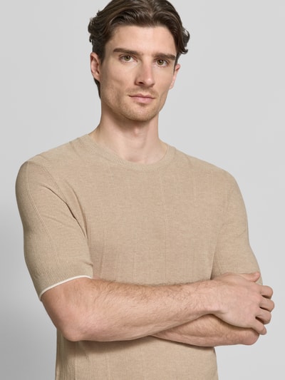 Męski model nosi Strickshirt mit Viskose-Anteil Modell 'Gion' od CINQUE, beżowy kolor, półrękaw, dekolt okrągły, widok na górną część ciała z przodu.