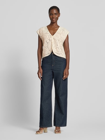 Frauenmodel trägt Strickweste mit V-Ausschnitt Modell 'Crossy' von FREE/QUENT in Beige mit Stickmuster, Baumwolle, Straight Fit, Ganzkörperansicht von vorne.