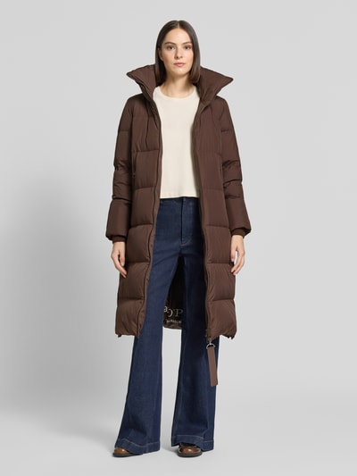 Frauenmodel trägt Regular Fit Daunenmantel mit abnehmbaren Rucksackriemen von Marc O'Polo in Dunkelbraun, glatte Oberfläche, Ganzkörperansicht von vorne, Damen Daunenmantel von Marc O'Polo.