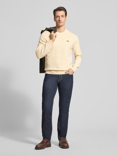 Männermodel trägt Regular Fit Strickpullover aus Baumwoll-Mix von Lacoste, Optik: Unifarben, Logo-Stitching. Ganzkörperansicht von vorne.