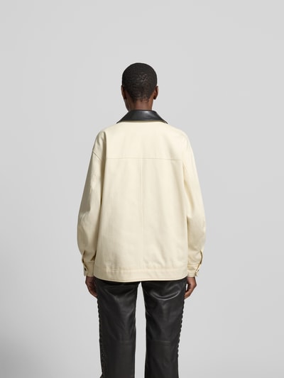 Frauenmodel trägt Relaxed Fit Jacke mit Umlegekragen von Anine Bing aus Reine Baumwolle, Creme mit schwarzen Details, Ganzkörperansicht Rückansicht, Rückenlänge 70 cm, Brustweite 59 cm, Ärmellänge 55 cm, AufgesetzteTaschen, Reißverschluss.