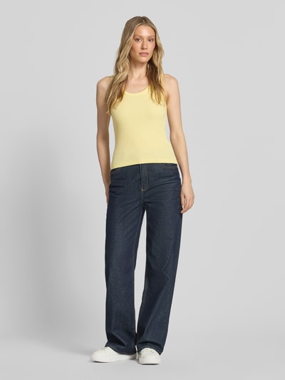 Modelka kobieca ma na sobie żółty Slim Fit Top aus Baumwoll-Mix Modell 'CHLOE' od Vero Moda, jednolita optyka, krój slim fit, dekolt U, faktura prążkowana, bawełniany miks, widok całej sylwetki z przodu.