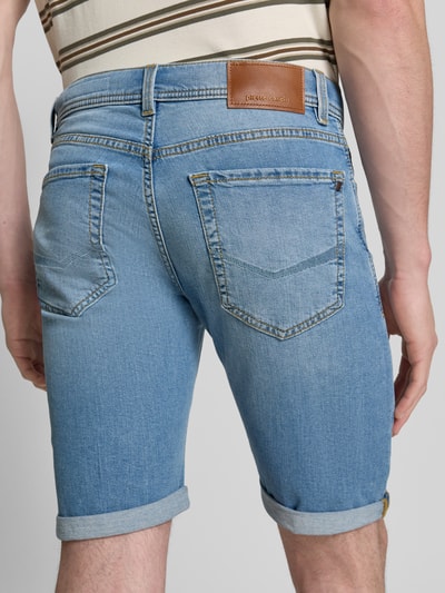Männermodel trägt Regular Fit Shorts in Denim-Optik von Pierre Cardin, hellblaue Baumwollstruktur, 5-Pocket-Design, Rückansicht Ganzkörperansicht.
