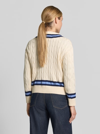 Frauenmodel trägt Regular Fit Pullover aus reiner Baumwolle von MANGO in Strick-Optik, V-Ausschnitt, cremefarben mit blauen Details, elastische Abschlüsse, Rückenansicht, Ganzkörperansicht Rückansicht.