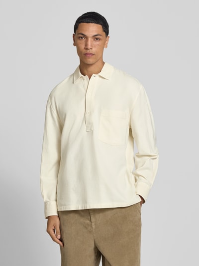 Männermodel trägt Regular Fit Poloshirt mit Brusttasche von Officine Générale in Beige, reine Baumwolle, Langarm, Ganzkörperansicht von vorne.