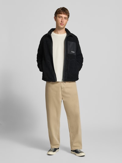 Männermodel trägt zwarte fleecejack Model 'SOHO' van JACK & JONES met Teddybont, regular fit, opstaande kraag, ritssluiting, steekzakken, borstzak met ritssluiting, Logo, Ruglengte maat M: 68 cm, Mouwlengte maat M: 69 cm, Ganzkörperansicht von vorne