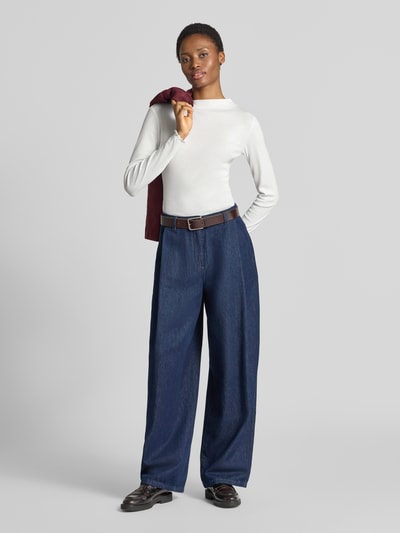 Frauenmodel trägt Slim Fit Langarmshirt aus Modal-Baumwoll-Mix Modell 'Soninchen' von OPUS in Weiß, kombiniert mit blauer Hose, Ganzkörperansicht von vorne.