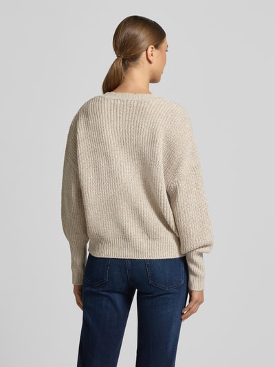 Vrouwenmodel draagt Relaxed Fit Strickjacke mit V-Ausschnitt Modell 'LEA' van Vero Moda in melange optiek, grof gebreid beige, lange mouwen, geribde boorden, eenrijige knopen, volledig rugaanzicht.