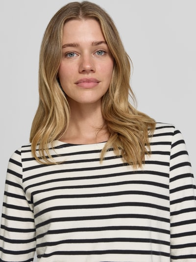 Modelka kobieca ma na sobie Regular Fit Langarmshirt aus reiner Baumwolle od Marc O'Polo, imitacja dzianiny, krój regular fit, wzór w paski, naszywka z logo, dekolt w łódkę, długi rękaw, wykończenie materiału: dzianina, materiał: czysta bawełna, kolory: biały i czarny, widok na górną część ciała z przodu.