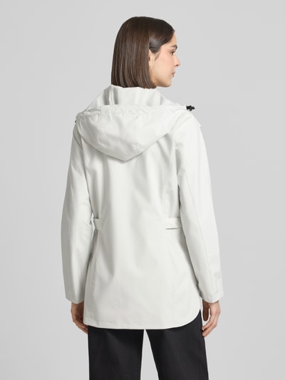 Vrouwenmodel draagt Regular Fit Regenmantel met logodetail van G.I.G.A. DX, witte kleur, steekzakken, tweewegritssluiting, capuchon met tunnelkoord, ruglengte 76 cm, schouderbreedte 40 cm, borstwijdte 50 cm, mouwlengte 66 cm, ganzekörperaanzicht achteraan.
