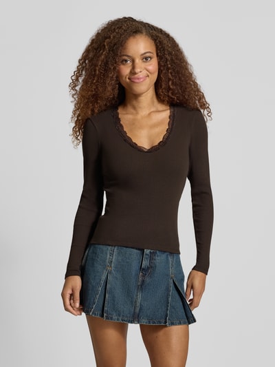Frauenmodel trägt Slim Fit Langarmshirt aus Baumwoll-Mix Modell 'SARA SHARAI' von ONLY in Dunkelbraun, strukturierte Oberfläche, Ganzkörperansicht von vorne. Damen Langarmshirt von ONLY.