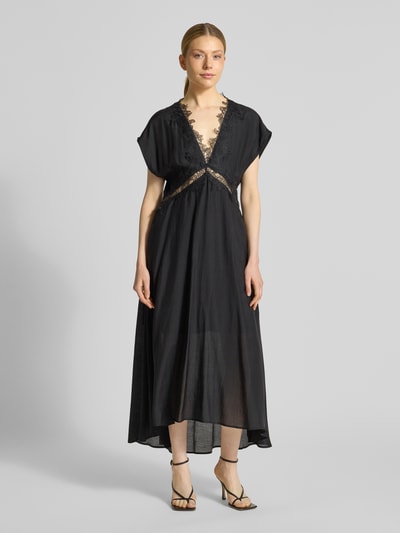 Kobiece modelka nosi Midikleid mit V-Ausschnitt und Spitze Modell 'MOLLY' von Copenhagen Muse, czarny lyocellowy materiał, koronkowe detale, krój slim fit, długość z tyłu w rozmiarze S: 139 cm, szerokość w rozmiarze S: 35 cm, widok całej sylwetki z przodu.