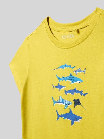 Produktfoto, T-Shirt mit Motiv-Print und Rundhalsausschnitt von Blue Seven, Kinder T-Shirt aus Reine Baumwolle, Regular-Fit, Motiv-Print mit verschiedenen blauen Fischen auf gelbem Stoff, Rückenlänge bei Größe 116: 42 cm.