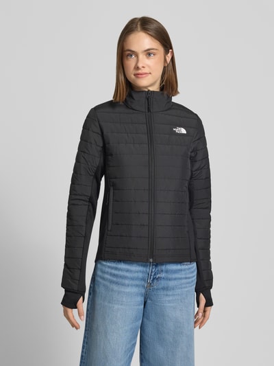 Frauenmodel trägt schwarze Steppjacke mit Logo Modell 'CANYONLANDS' von The North Face, Stehkragen, Reißverschluss, Frontansicht, Ganzkörperansicht von vorne.