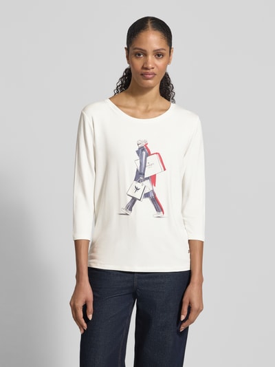 Frauenmodel trägt Regular Fit Longsleeve aus Viskose-Mix mit Ziersteinbesatz von monari, elastischer Viskose-Mix mit Modal-Anteil, 7/8-Arm, Logo-Print, Motiv-Print, Rundhalsausschnitt, Rückenlänge bei Größe 36: 59 cm, in Creme und Dunkelblau, glatte Textur. Ganzkörperansicht von vorne.