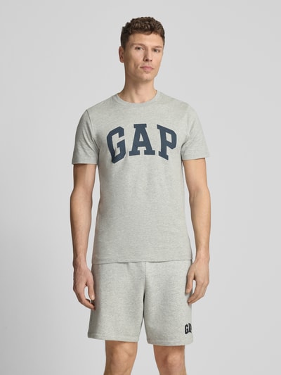 Männermodel trägt T-Shirt mit Logo und Rundhalsausschnitt von GAP, Herren T-Shirt aus Reine Baumwolle, Regular-Fit, hellgrau, Ganzkörperansicht von vorne. Rückenlänge bei Größe M 72 cm