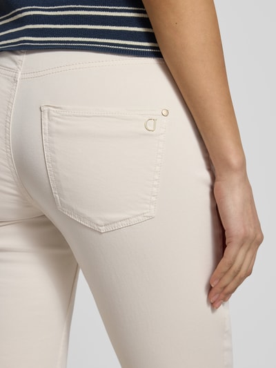 Kobieta prezentuje spodnie Cropped Hose mit Eingrifftaschen model 'PIPER' von Cambio z bawełny, krój slim fit, kremowy kolor, detal tylnej kieszeni, zbliżenie na biodro