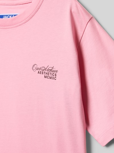 Meisje draagt T-shirt met Label-Print model 'ROAR' van Jack & Jones in roze katoen, regular fit, geribbelde ronde hals, detailopname.