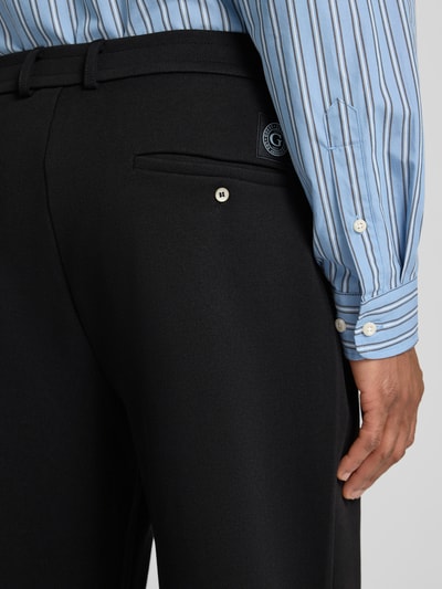 Mężczyznamodel nosi Straight Fit Stoffhose mit Bundfalten od Guess, czarna tkanina, detal tylnej kieszeni, bawełniany miks, perspektywa: zbliżenie tylnej części. Szerokość w rozmiarze M: 42 cm, długość nogawki od wewnątrz: 81 cm.