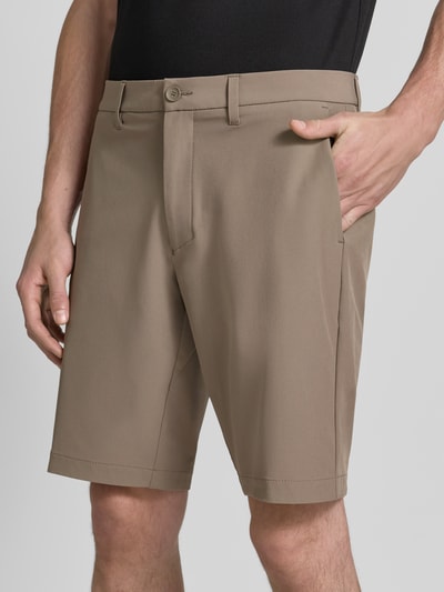 Mannenmodel draagt Slim Fit Chinoshorts met persplooien van BOSS Green in lichtbruin, gladde textuur, detailopname voorkant.