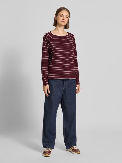 Frauenmodel trägt Regular Fit Langarmshirt aus reiner Baumwolle von Marc O'Polo DENIM mit weinroten und weißen Streifen, weite Jeans, Ganzkörperansicht von vorne.
