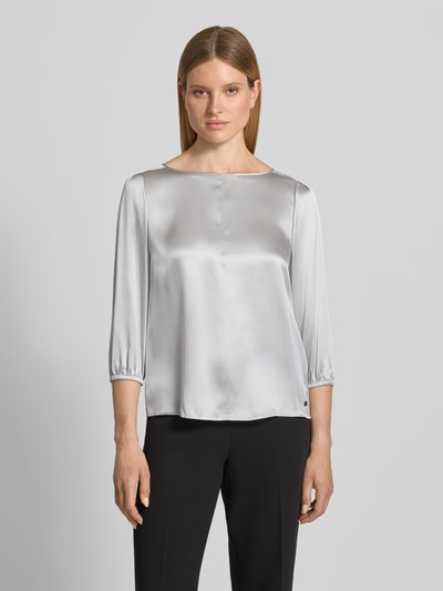 Kobiece model prezentuje Blusenshirt aus Seide mit 3/4-Arm od Marc Cain, srebrzystoszary jedwab, krój regular fit, okrągły dekolt, długość tyłu w rozmiarze 36: 60 cm, długość rękawów w rozmiarze 36: 49 cm, widok całej sylwetki z przodu.