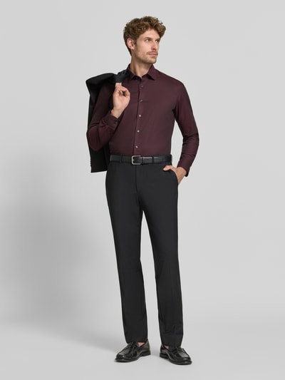 Männermodel trägt Body Fit Businesshemd aus Baumwoll-Mix von OLYMP in Dunkelrot mit schwarzer Hose, Ganzkörperansicht von vorne. Herren Businesshemd von OLYMP Level 5