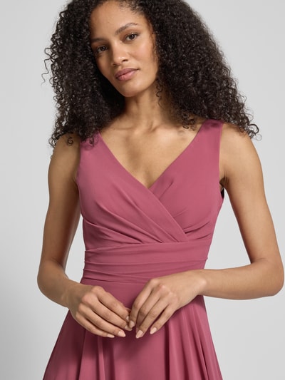 Modelka kobieca nosi knielanges Cocktailkleid aus Chiffon mit V-Ausschnitt od TROYDEN COLLECTION, róż, krój taliowany, dekolt V, długość do kolan, szerokość w rozmiarze 36: 34 cm, długość tyłu: 87 cm, długość rękawa: 108 cm, tkanina lekko marszczona, miękka faktura, zbliżenie na górną część ciała.