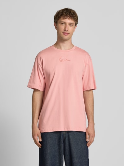 Männermodel trägt Regular Fit T-Shirt mit Logo-Stitching von KARL KANI in Rosa aus Reine Baumwolle, Rundhalsausschnitt, Ganzkörperansicht von vorne. Rückenlänge bei Größe M: 73 cm.