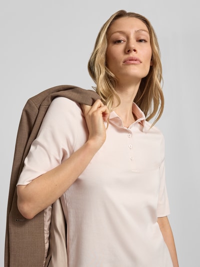 Frauenmodel trägt Slim Fit Poloshirt mit Knopfleiste und 1/2-Arm von Christian Berg Woman aus Reine Baumwolle, Nahaufnahme Oberkörper. Rückenlänge bei Größe 36: 61 cm.