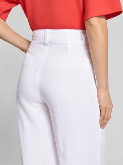 Frauenmodel trägt Wide Fit Stoffhose aus Viskose-Mix mit Leinen-Anteil von Marc Cain, weiß, mit Paspeltaschen, Logo-Detail, Detailaufnahme Rückansicht. Kontext: Damen Stoffhose, Bundweite bei Größe 36: 37 cm, Innenbeinlänge bei Größe 36: 82 cm, Eingrifftaschen, Wide-Fit, Leinen-Viskose-Anteil.