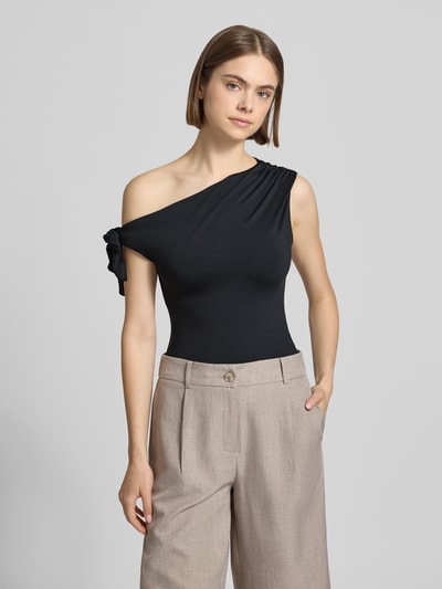 Frauenmodel trägt Damen T-Shirt im One-Shoulder-Look von Gina Tricot, Material-Mix mit Stretch-Anteil, Slim-Fit, Knotendetail, Rückenlänge bei Größe S 51 cm, schwarze Farbe, glatte Textur, Ganzkörperansicht von vorne.