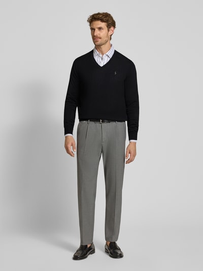 Männermodel trägt Regular Fit Pullover aus reiner Wolle von Polo Ralph Lauren in Schwarz vor hellem Hintergrund, Ganzkörperansicht von vorne.