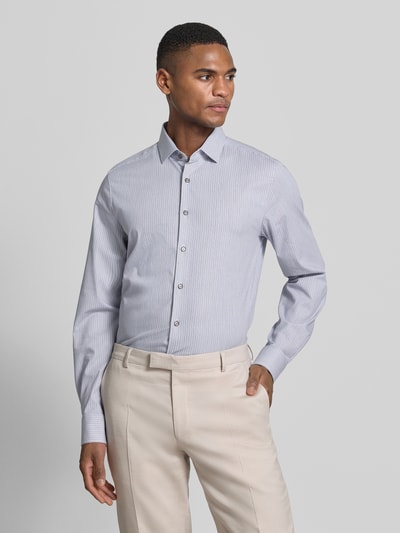 Männermodel trägt Slim Fit Business-Hemd mit Kentkragen von OLYMP Level Five, Baumwoll-Mix mit Stretch-Anteil, feine Streifen, Knopfleiste, Ganzkörperansicht von vorne.