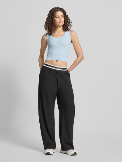 Frauenmodel trägt Slim Fit Top mit Logo-Detail von ANOTHER COTTON LAB in Hellblau, glatter elastischer Baumwoll-Mix, Rundhalsausschnitt, Ganzkörperansicht von vorne.