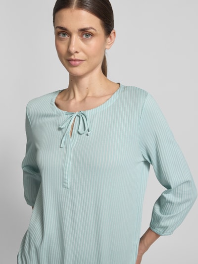 Frauenmodel trägt Regular Fit T-Shirt aus Baumwoll-Mix von Tom Tailor in Hellblau mit feinen Streifen, V-Ausschnitt und langen Ärmeln, Feinripp-Textur, Nahaufnahme Oberkörper.