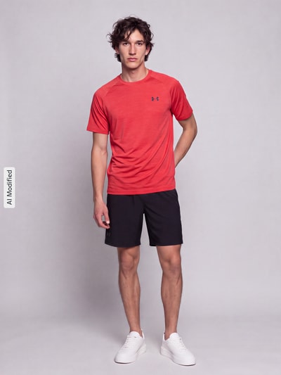 Männermodel trägt Regular Fit Sport-T-Shirt mit Logo-Print von Under Armour in Rot, kombiniert mit schwarzen Shorts, Ganzkörperansicht von vorne, KI-modifiziertes Bild. Herren Sport-T-Shirt von Under Armour.