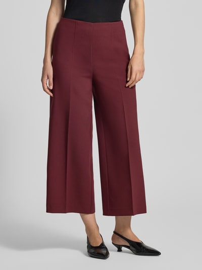 Frauenmodel trägt Stoffhose mit Bügelfalte und Eingrifftaschen von MORE & MORE in Dunkelrot, Material-Mix, Wide Leg Fit, Nahaufnahme Oberkörper.