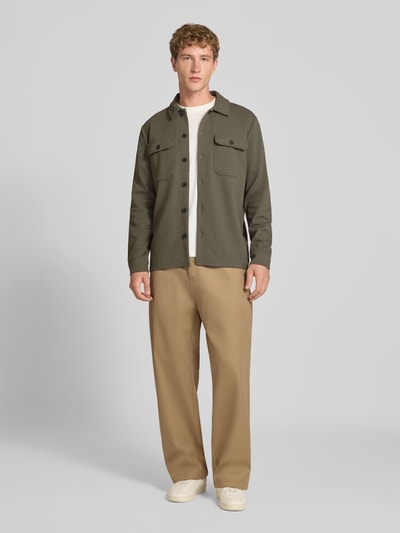 Männermodel trägt Relaxed Fit Hemdjacke mit Viskose-Anteil Modell 'NEWKODYL' von ONLY in Oliv, beige Hose, dezente Textur, Ganzkörperansicht von vorne. Herren Hemdjacke von ONLY & SONS.