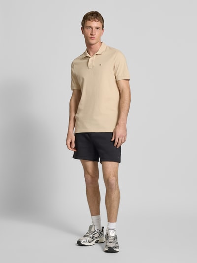Männermodel trägt Regular Fit Poloshirt aus reiner Baumwolle von Tommy Jeans in Optik: Unifarben, Piqué-Struktur, Logo-Stitching, Ganzkörperansicht von vorne.