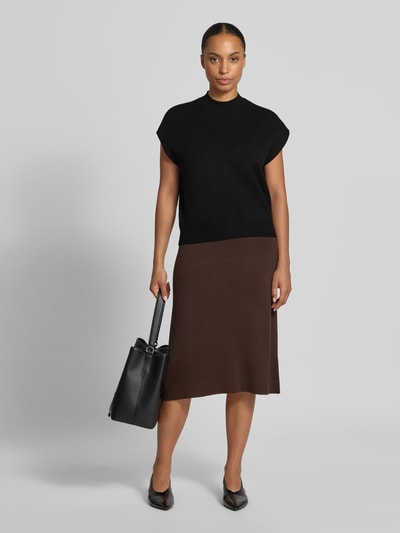 Frauenmodel trägt Loose Fit Pullover aus Viskose-Baumwoll-Mix Modell 'ELLY' von VERO MODA in Schwarz, kombiniert mit braunem Rock, schlichte Farben, glatte Texturen, Damen Pullover von VERO MODA, Ganzkörperansicht von vorne.