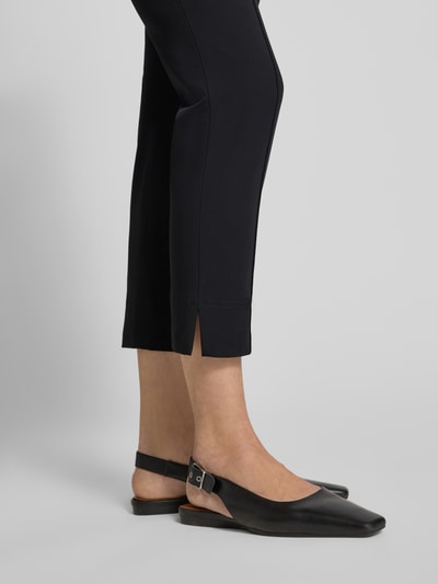 Frauenmodel trägt Caprihose mit Längsnähten Modell 'CAPRI' von SEDUCTIVE in Schwarz, glatte Textur, Nahaufnahme Unterschenkel, Material-Mix mit Baumwoll-Anteil, Regular Fit