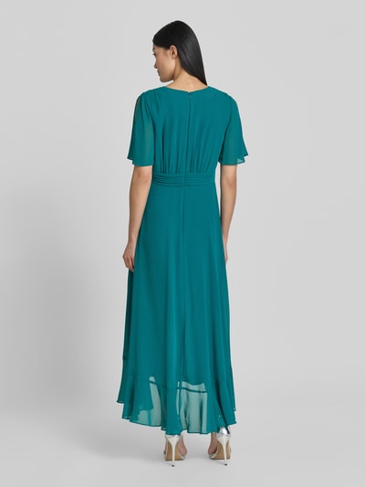 Modelka nosi 'Cocktailkleid in Wickel-Optik' od Christian Berg Cocktail w kolorze zielonym, z szyfonu, krój dopasowany, długość midi, pasek wiązany, szerokość w rozmiarze 36: 40 cm, długość tyłu: 35 cm, długość rękawa: 29 cm, widok całej sylwetki od tyłu.