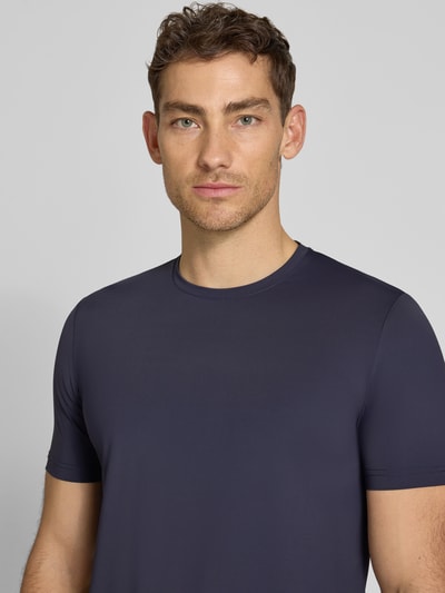 Männermodel trägt T-Shirt mit Rundhalsausschnitt Modell 'TESSUTO' von MARKUP in Dunkelblau, glatte Textur, Nahaufnahme Oberkörper, Modern Fit, Nylon-Mix mit Stretch-Anteil, Label-Detail sichtbar.