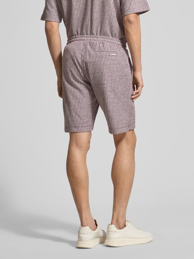 Männermodel trägt Regular Fit Shorts aus Viskose-Mix Modell 'CIARI' von CINQUE, rot-weiß gestreift, elastischer Bund, Rückansicht ganzkörper.