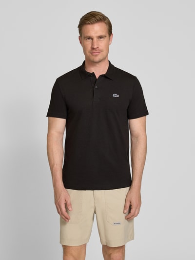 Männermodel trägt Regular Fit Poloshirt aus Baumwoll-Mix von Lacoste, Optik: Unifarben, Logo-Patch, Polokragen, Kurzarm, Ganzkörperansicht von vorne.