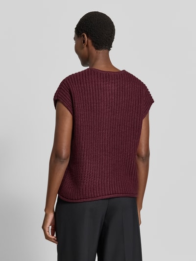 Kobiece model prezentuje kamizelkę dzianinową Relaxed Fit Strickweste mit Woll-Anteil Model 'Norma' od b.young, Mieszanka materiałów z dodatkiem wełny, okrągły dekolt, krótkie rękawy, jednolita bordowa tekstura, listwa guzikowa z przodu, Długość tyłu w rozmiarze S: 52 cm, widok całej sylwetki z tyłu.